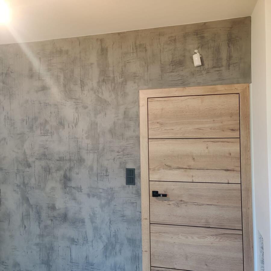 Ściana z efektem betonu architektonicznego i drzwiami w dębie
